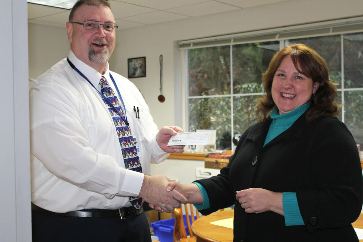 Battle Ground: Summit View High School Principal Bill Penrose, left, greets Chris Burt from the Battle Ground Education Foundation as she handed him a scholarship check for $300.