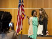 Amina Idy of Portland, holding flag, celebrates her U.S. citizenship Tuesday by having her photograph taken with friend Megan Tragethon at the Vancouver Community Library.