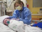 Kristina Kinnunen cares for a 3-week-old boy in the pediatric wing at Legacy Salmon Creek Medical Center on Nov. 14. Kinnunen started her career at Legacy as a housekeeper.