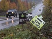 A motorist driving on North 45th Avenue passes signs advertising new houses for sale on Nov. 19 in Ridgefield.