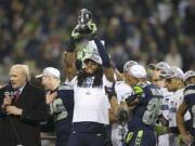 Richard Sherman hoists the George Halas Trophy with teammates after the NFC Championship game against the San Francisco 49ers at CenturyLink Field on Sunday.