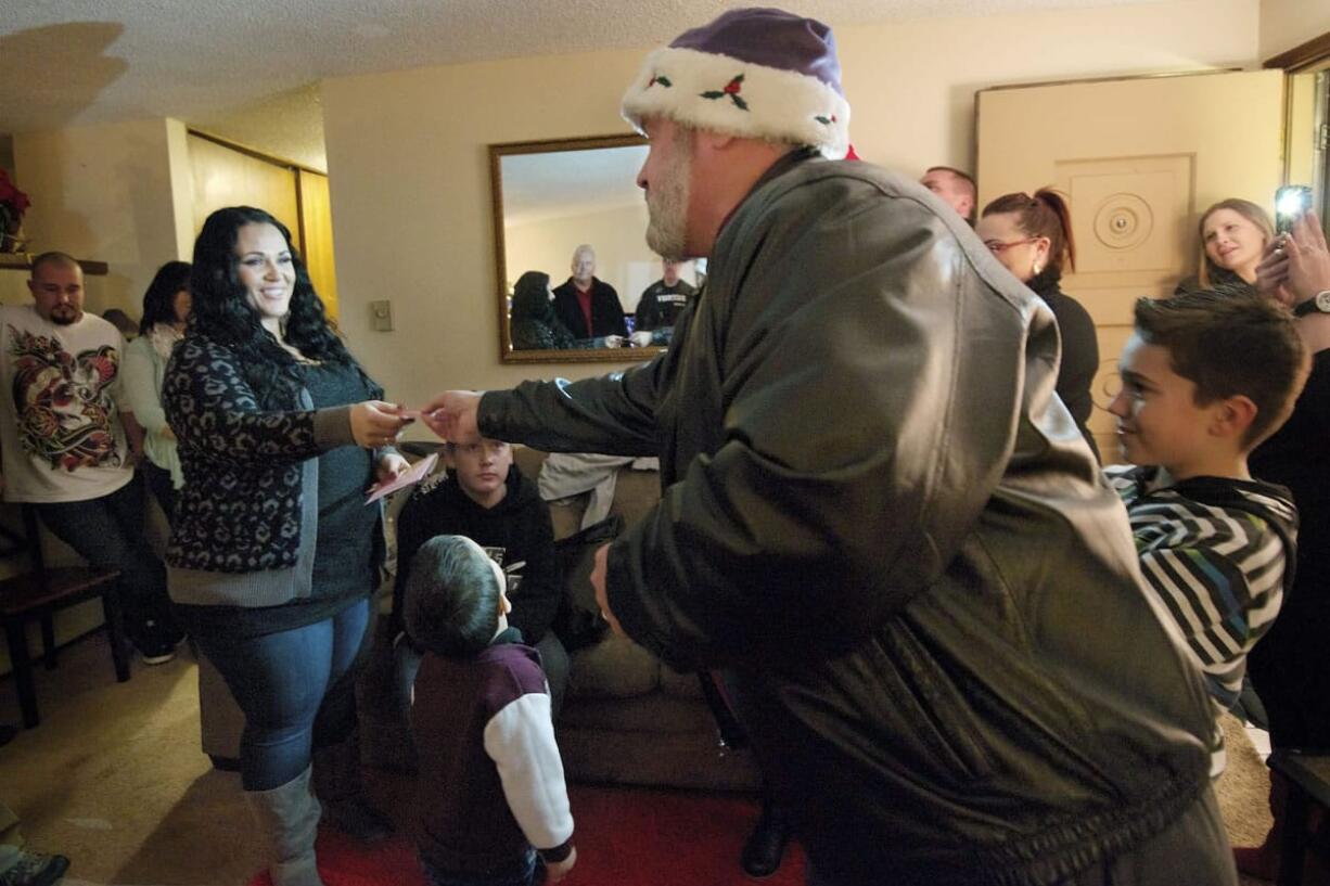 Sean Guard, right, hands Debra Deblander gift cards donated by local businesses and community members who wanted to help after learning Deblander's home was burglarized less than two weeks before Christmas.