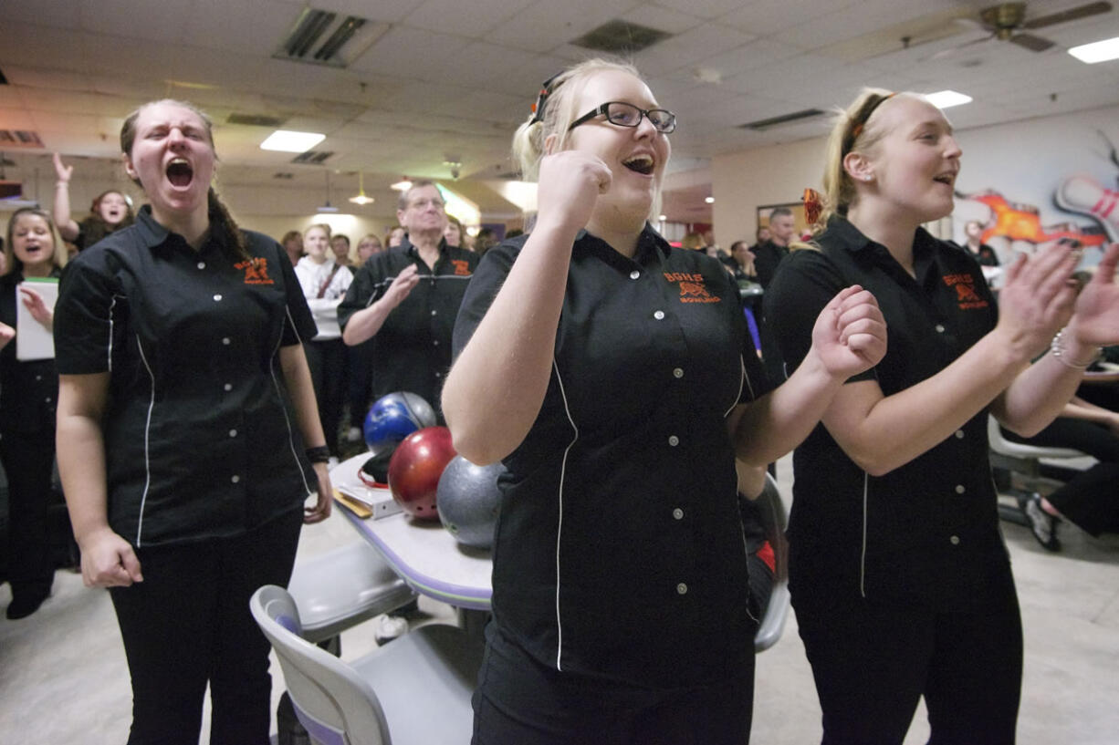 AJ Schock, left, Wylicia Faley, center, and Kim Martin of Battle Ground High School, celebrate as teammate Cassie Huit bowls a strike during the 4A district girls bowling championships Friday January 31, 2014 in Vancouver, Washington.