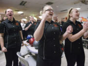 AJ Schock, left, Wylicia Faley, center, and Kim Martin of Battle Ground High School, celebrate as teammate Cassie Huit bowls a strike during the 4A district girls bowling championships Friday January 31, 2014 in Vancouver, Washington.