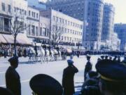 Holding a camera over his head, John Van Zytveld captured a photo of the caisson bearing the flag-draped coffin of John F. Kennedy on Nov. 25, 1963. Right: The caisson bearing John F. Kennedy's coffin rolls past mourners on the way to the cathedral on Nov.