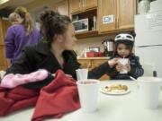 Kayla Baker, left, helps her daughter Samona Samoeun, 2, drink hot chocolate at the Winter Hospitality Overflow shelter at St. Andrew Lutheran Church in Orchards. The shelter houses women, couples and families with children.