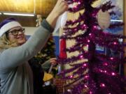 Home Instead Senior Care President Julie Williams hangs paper ornaments on a small Christmas tree Wednesday at the Marshall Center, which list modest gifts for seniors in need and gives the public a chance to play Santa Claus.