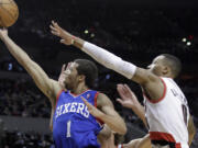 Philadelphia 76ers guard Michael Carter-Williams, left, goes to the hoop against Portland Trails Blazers guard Damian Lillard during the first half of an NBA basketball game in Portland, Ore., Saturday, Jan. 4, 2014.