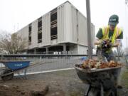 Kai Stevenson with Eco Safe Landscape Construction and Maintenance cleans the area outside Vancouver's former city hall building, which has been renamed Block 56.