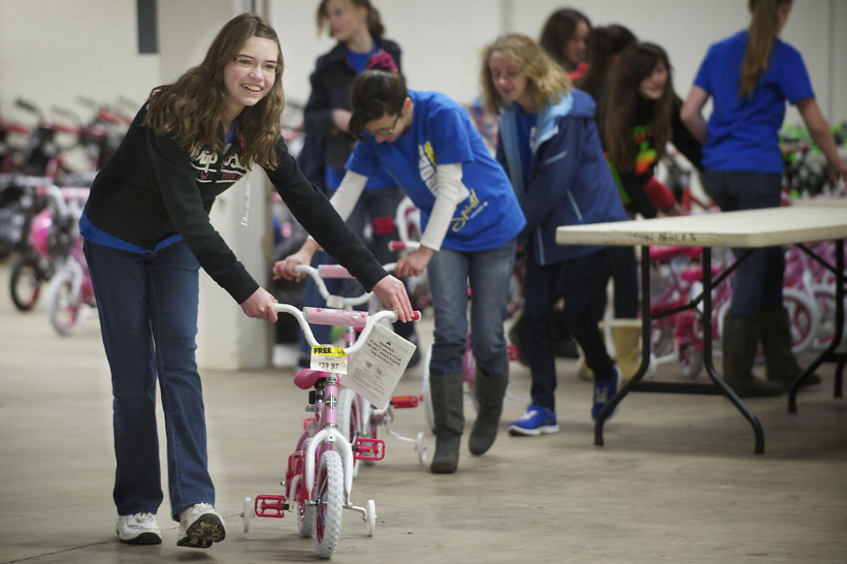 Thirteen-year-old Maggie Mayer, a student at Our Lady of Lourdes Catholic School, leads a line of brand new bikes that will be given to needy families via Santa's Posse, a charitable effort led by the Clark County Sheriff's Office and local Rotary clubs. The bikes were donated by Waste Connections as part of its Christmas Promise program.