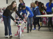 Thirteen-year-old Maggie Mayer, a student at Our Lady of Lourdes Catholic School, leads a line of brand new bikes that will be given to needy families via Santa's Posse, a charitable effort led by the Clark County Sheriff's Office and local Rotary clubs. The bikes were donated by Waste Connections as part of its Christmas Promise program.