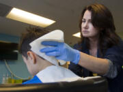 Janet Kennedy Unitan, director of the lice removal company Lice Knowing You, checks a boy's head for lice Tuesday in the company's Portland clinic.