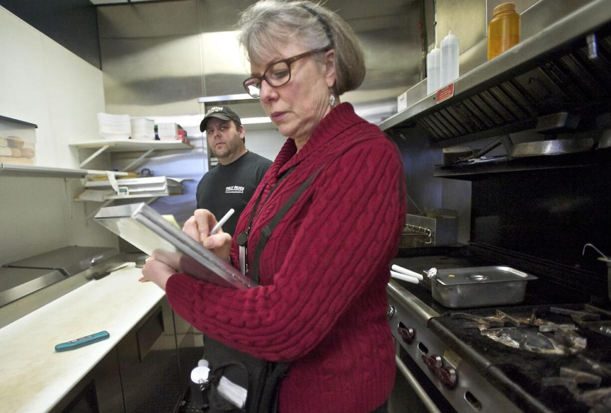 Joan Lacey, a food safety specialist with Clark County Public Health, records food temperatures during an inspection of Philly Bilmos Cheesesteaks as owner Michael Bitter watches. Lacey performs three unannounced inspections of the restaurant each year; it received a perfect score Jan.