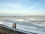 A pair of women stop at the edge of Vancouver Lake to take photos and look at the ice and snow Wednesday.