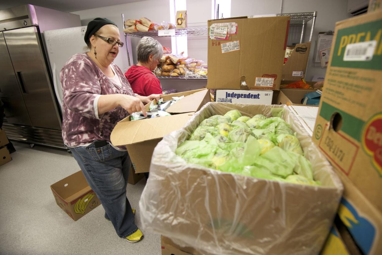 Volunteers Donna Cologna, left, and Sandra Ree stock the new One Life food pantry in advance of doors opening on Sunday afternoon.