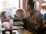 Melissa Murdock, 26, and three of her daughters, from left, Angel Raptopoulos-Hair, 8 months, Julie Walker, 3, and Rayne Walker, 4, enjoy being together at Chronis' Restaurant and Lounge during the annual free Thanksgiving meal.