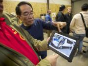 Photos by Steven Lane/The Columbian
Roberto Martin, national president of Pasang Masda, right, and Rogel Fernandez, national coordinator of Pasang Masda, show a video of a Comet, the 16-passenger electric van designed by Pangea Motors.