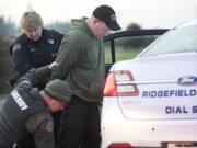 A Ridgefield police officer and a sheriff deputy arrest a man during an investigation of a home invasion robbery on Thursday afternoon.