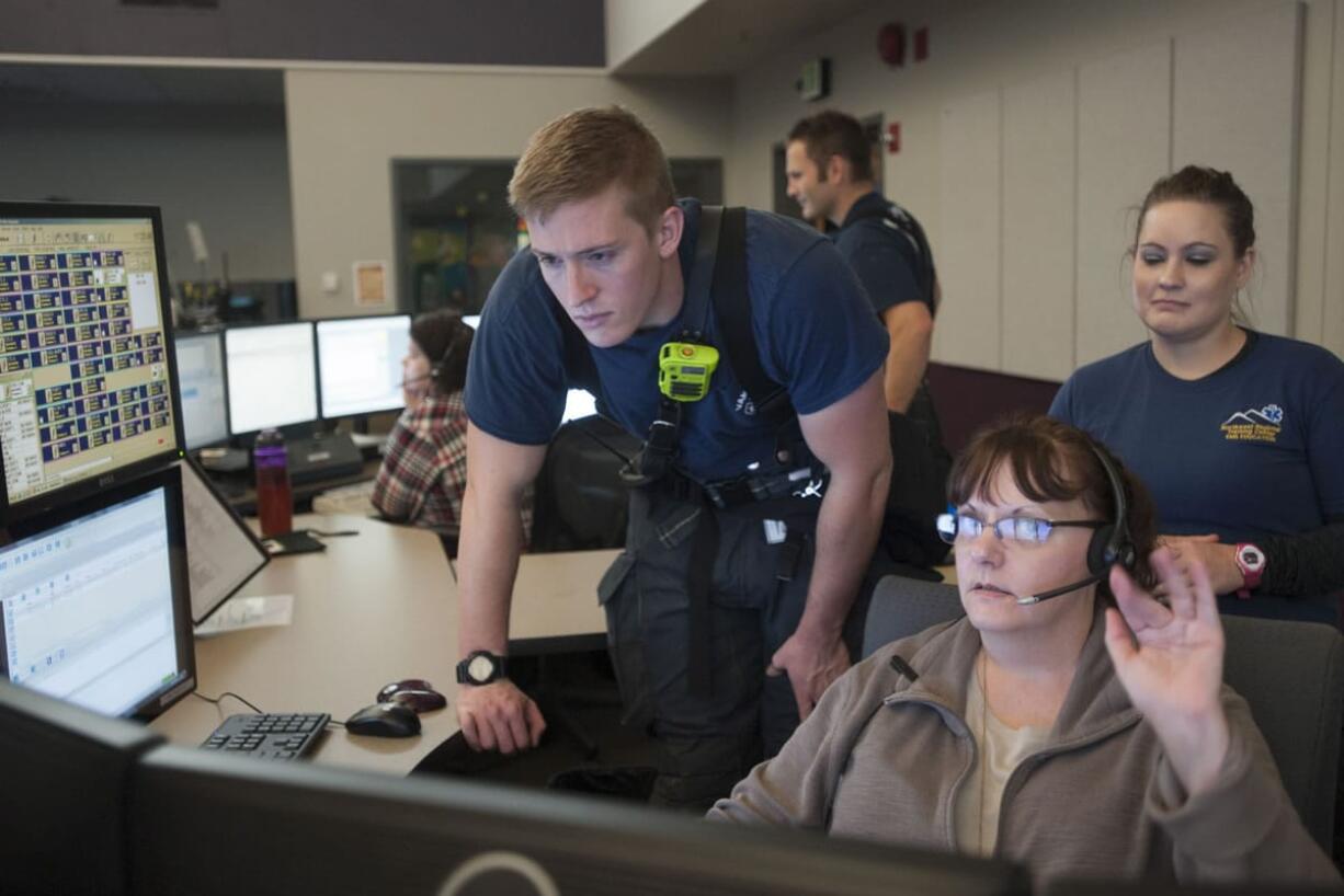 Dispatcher Robin Bardon, right, shows rookie firefighter Spencer Vadney how 911 calls are handled Nov. 17 at the Clark Regional Emergency Services Agency in Vancouver. In 2014, the most common calls were incomplete calls.