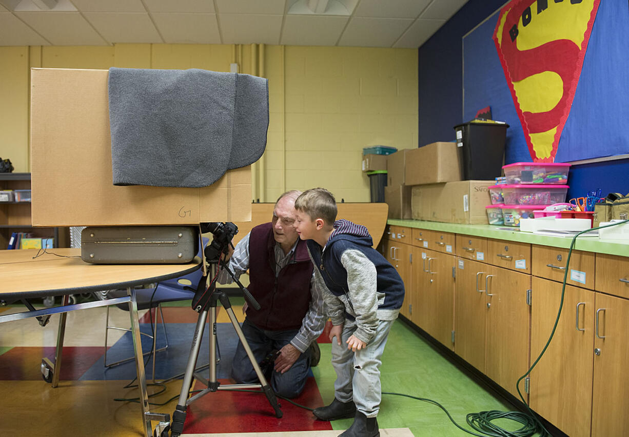 Volunteer Ray Klein works with 7-year-old Favian McDowell Garza to make an abstract &quot;vision of light&quot; out of very basic materials: a darkened box with a light bulb inside and a 30-second photographic exposure.