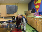 Volunteer Ray Klein works with 7-year-old Favian McDowell Garza to make an abstract &quot;vision of light&quot; out of very basic materials: a darkened box with a light bulb inside and a 30-second photographic exposure.