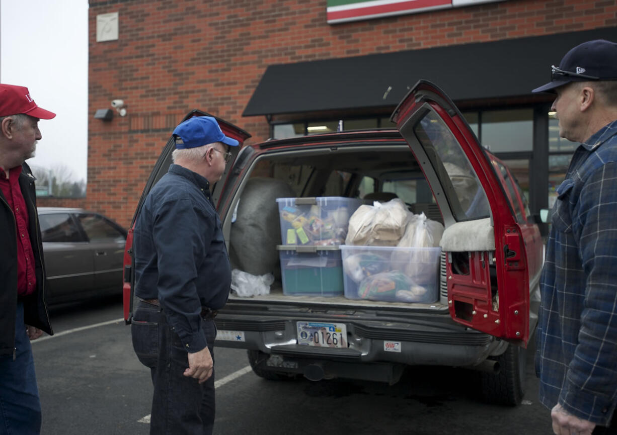 George Golden, center, director of LINKS, Michael Rankin, left, and Don Meuchel pick up perishable food items at a 7-Eleven in Vancouver on Friday.