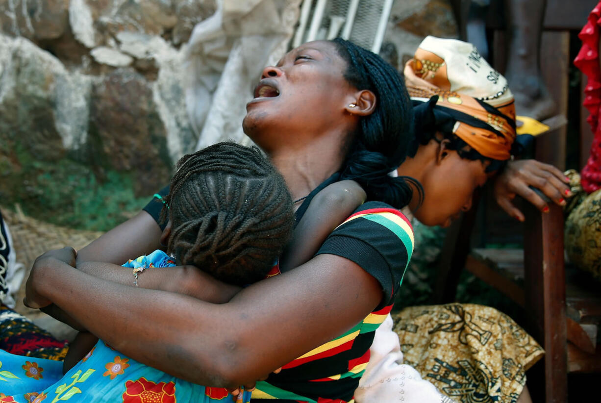 Relatives of Thierry Tresor Zumbeti, who died from bullet wounds to the neck and stomach, grieve outside his home in Bangui, Central African Republic, Saturday,  Dec. 7, 2013. Zumbeti was buried beside his house. Christians fearing reprisal attacks from the Muslim ex-rebels who control Central African Republic fled on foot by the thousands Saturday, as others ventured outside for the first in time in days only to bury their dead following the worst violence to wrack the lawless country in months.