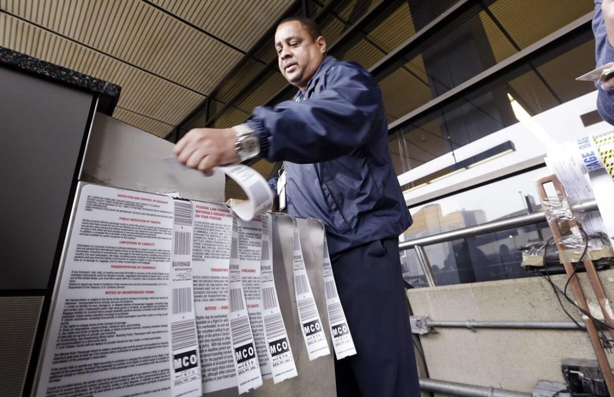 Veteran skycap Fred Harris prepares multiple baggage tags for a traveler at Seattle-Tacoma International Airport in SeaTac in october.