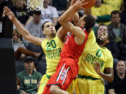 Oregon's Waverly Austin, left, fouls Arizona's Aaron Gardon as he defends the basket with teammate Oregon's Mike Moser, right, during the first half of an NCAA college basketball game in Eugene, Ore. on Saturday, March 8, 2014.