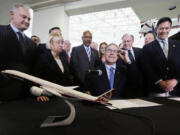 Gov. Jay Inslee, center, adjusts his glasses as he prepares to sign legislation to help keep production of Boeing's new 777X in Washington on Monday at the Museum of Flight in Seattle.