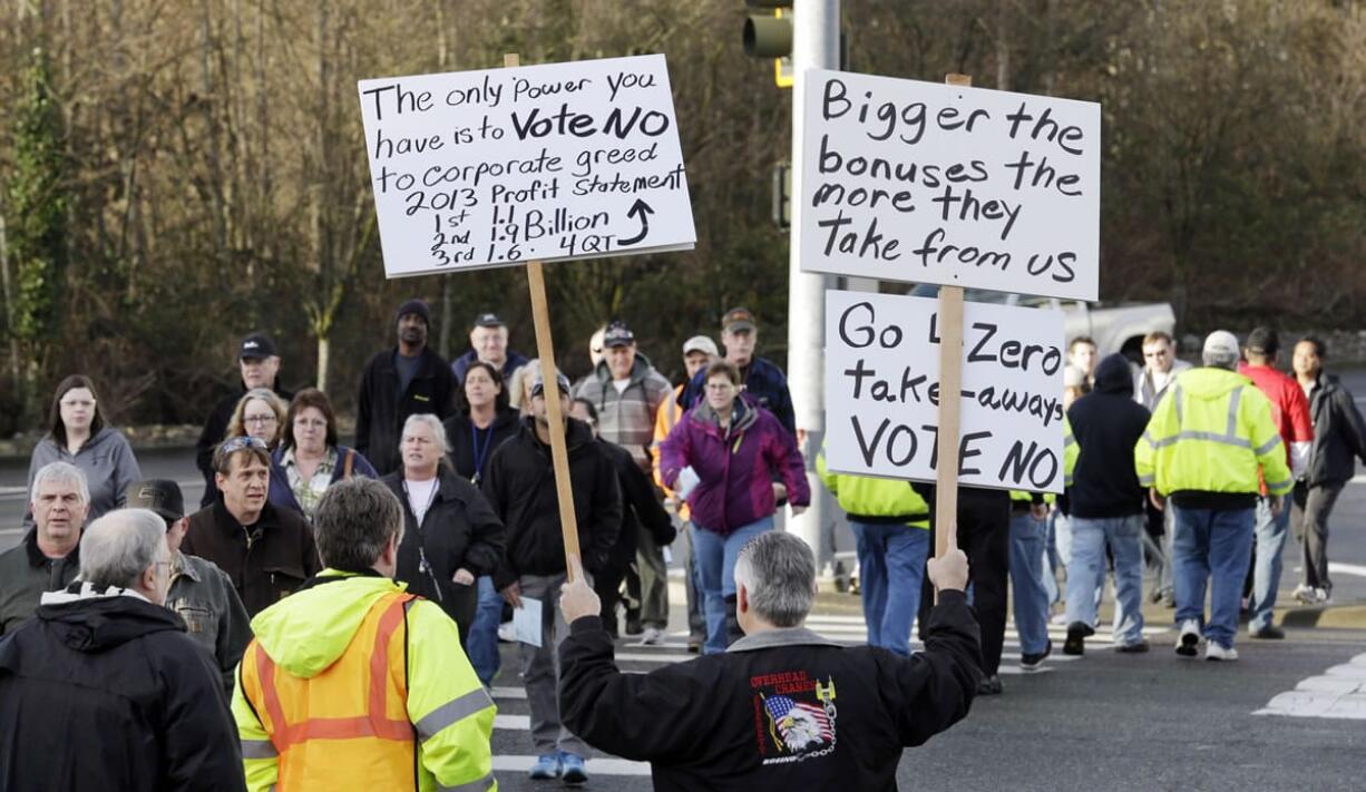 Boeing machinist Eddie Bjorgo greets fellow workers heading to a union hall to cast ballots with signs urging a &quot;no&quot; vote Friday in Everett.