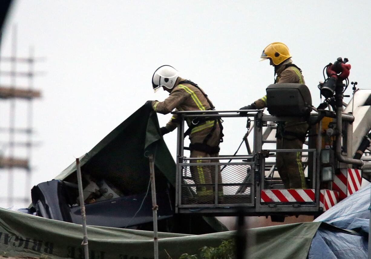 Scottish Fire and Rescue services look at the exposed part of the helicopter tail fin and rotor at the scene on Saturday, Nov. 30, 2013, following the helicopter crash at the Clutha Bar in Glasgow, Scotland. Scottish emergency workers were sifting through wreckage Saturday for survivors of a police helicopter crash onto a crowded Glasgow pub that has killed several people and injured dozens. The Clutha pub, near the banks of the River Clyde, was packed Friday night and a ska band was in full swing when the chopper slammed through the roof. The number of fatalities is expected to rise, officials said.