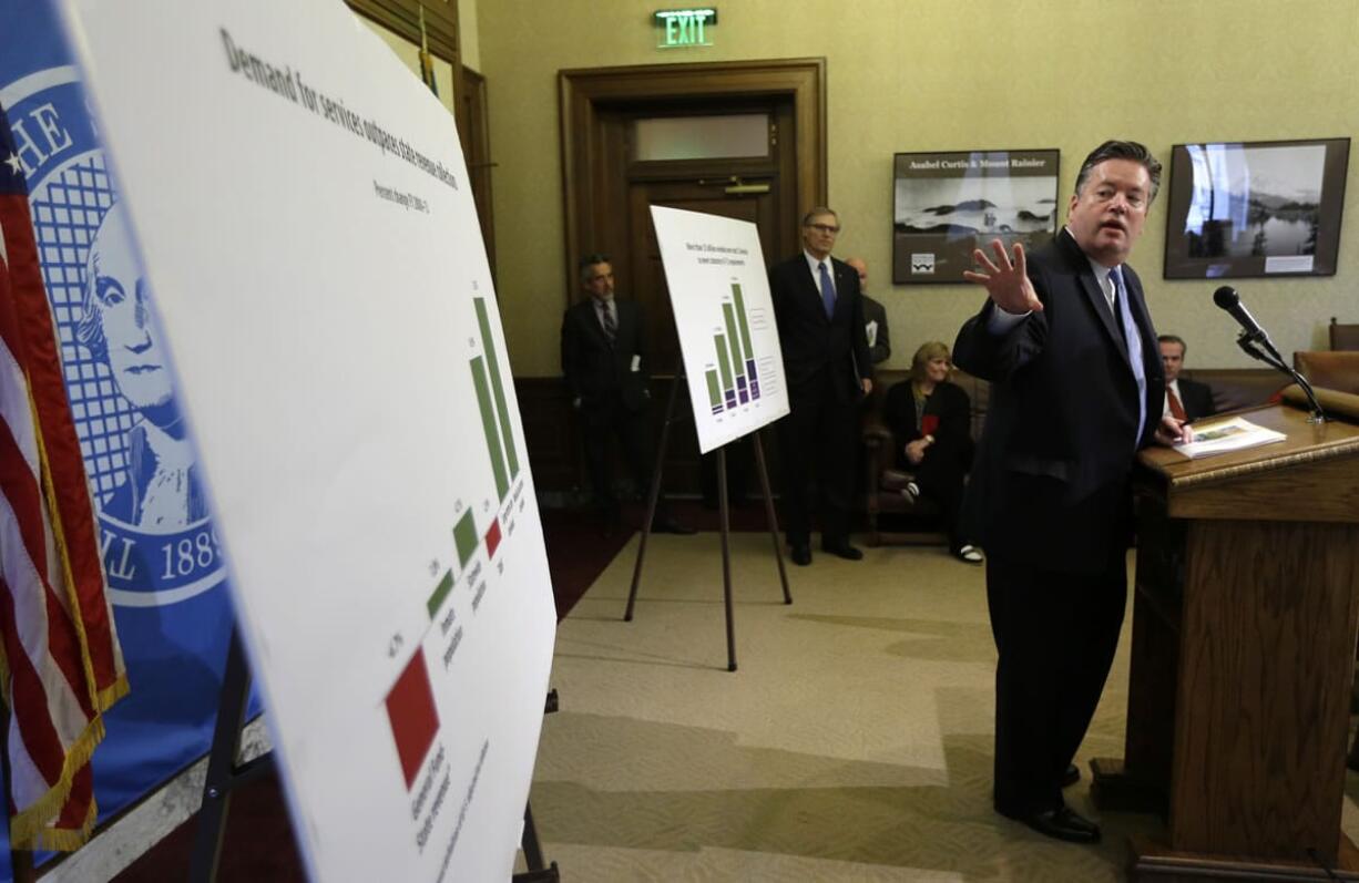 David Schumacher, right, Gov. Jay Inslee's budget director, talks to reporters, Tuesday, Dec. 17, 2013, at the Capitol in Olympia, Wash., about the Governor's supplemental budget. The budget proposes additional spending to address overcrowded prisons, increasing school enrollment numbers, and other expenses, including wildfire costs. (AP Photo/Ted S.