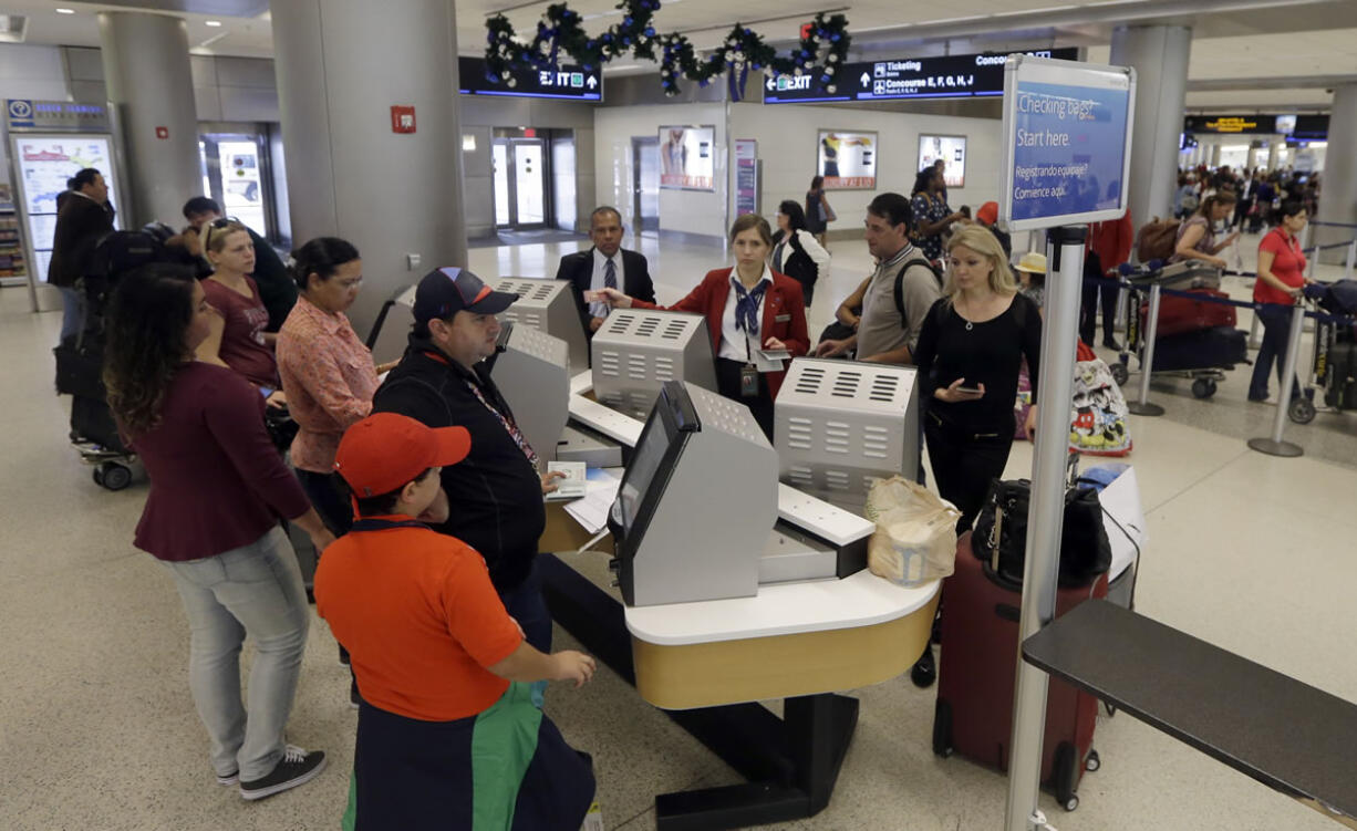 Travelers check in their luggage as they prepare to travel at Miami International Airport in Miami.