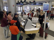 Travelers check in their luggage as they prepare to travel at Miami International Airport in Miami.