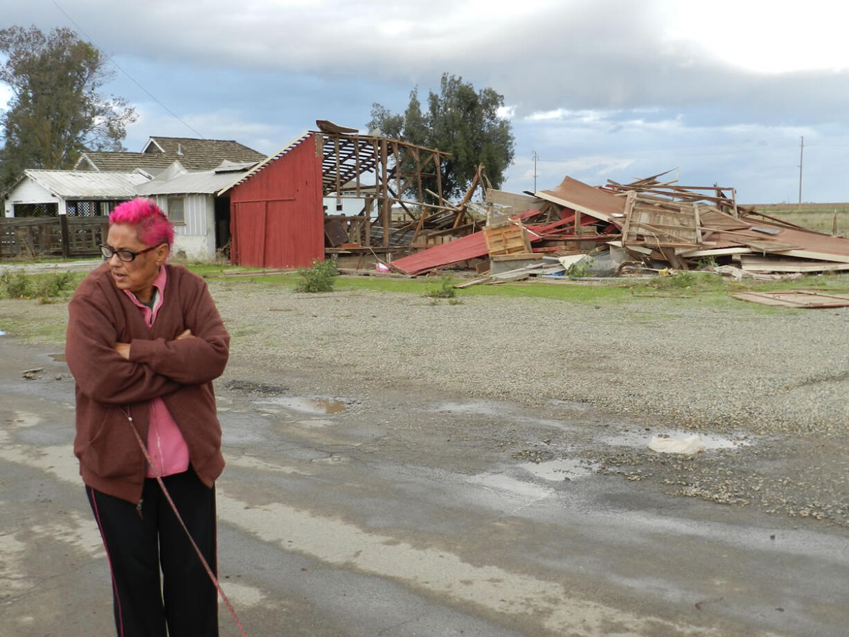 Sabina Woodard stands across the street from her destroyed barn Sunday after reports of a rare tornado in Denair, Calif. The National Weather Service said video and witness reports confirm a tornado touched down in Denair, tearing roofing and walls, knocking down trees and power lines and damaging gas lines.