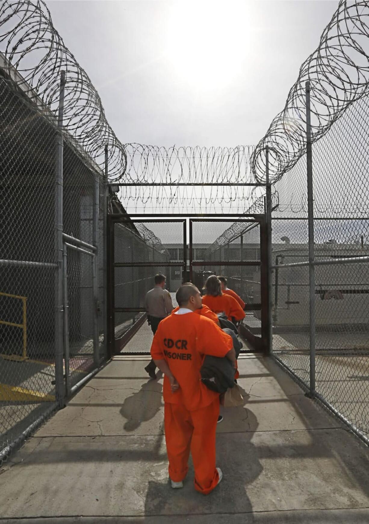 With belongings in hand, new arrivals to the Deuel Vocational Institution are taken inside the prison near Tracy, Calif., on Feb.