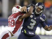 Seattle Seahawks quarterback Russell Wilson (3) is hit by Arizona Cardinals cornerback Justin Bethel just after getting a pass off during the second half of an NFL football game, Sunday, Nov. 15, 2015, in Seattle.