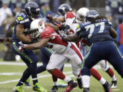 Seattle's Marshawn Lynch, left, is tackled by Arizona's Jake Ballard in Sunday's game.