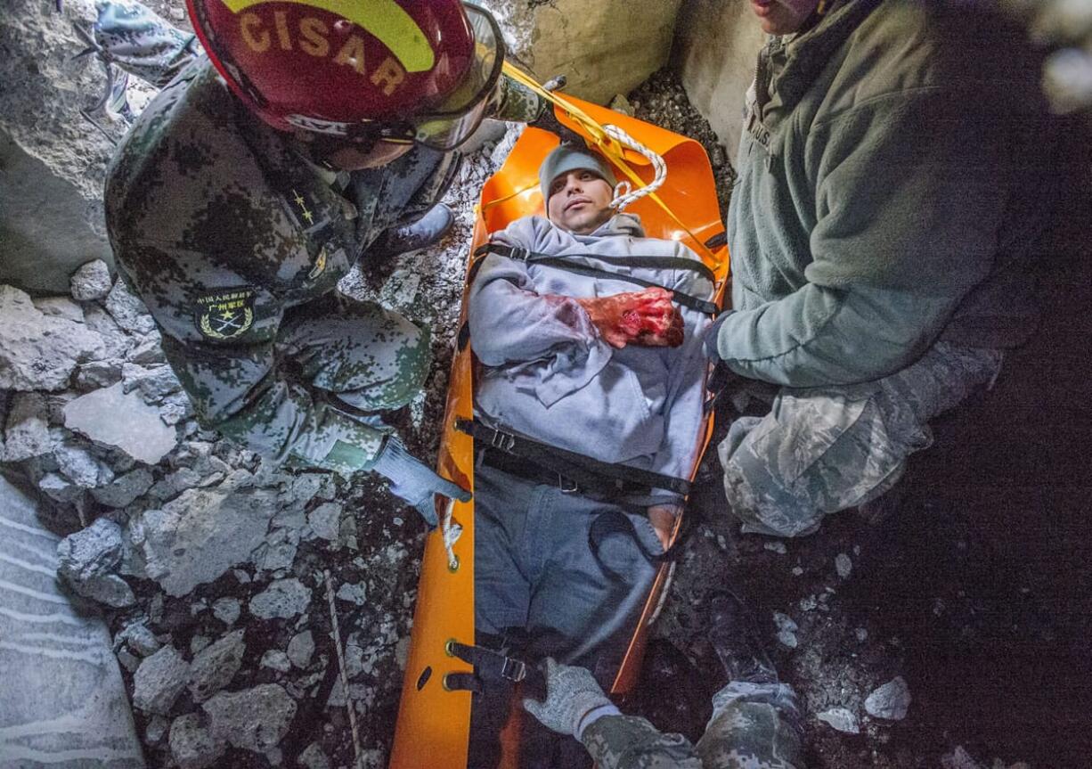 Chinese and American military personnel practice in a cramped space simulating the extraction of an injured person from a collapsed building, part of the 11th Disaster Management Exchange between the U.S and China military at Joint Base Lewis-McChord near Tacoma on Friday.  Top: A Chinese soldier wears a pin with American and Chinese flags.