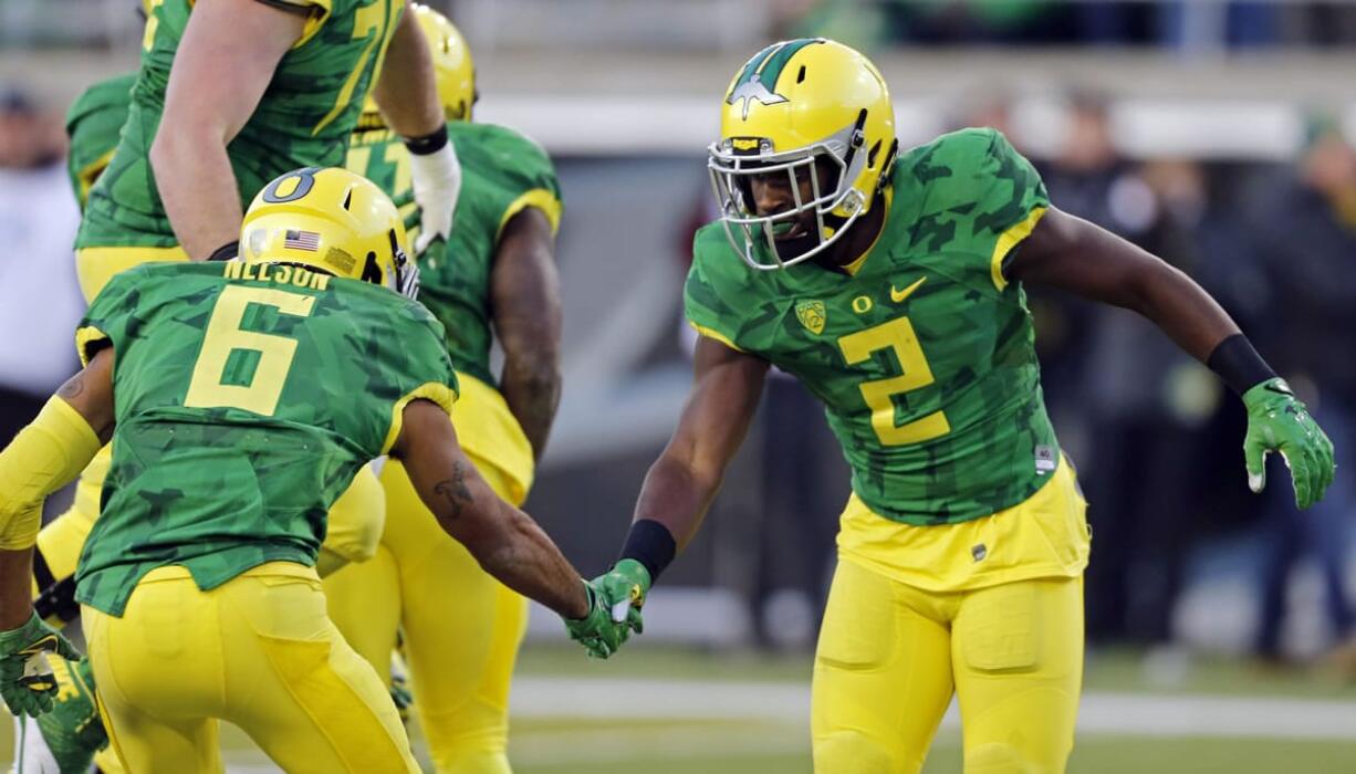 Oregon wide receiver Bralon Addison, right, shakes hands with teammate Charles Nelson after scoring a touchdown in the second half  of an NCAA college football game against Oregon State, in Eugene Ore., on Friday, Nov. 27, 2015. Oregon won 52-42. (AP Photo/Timothy J.