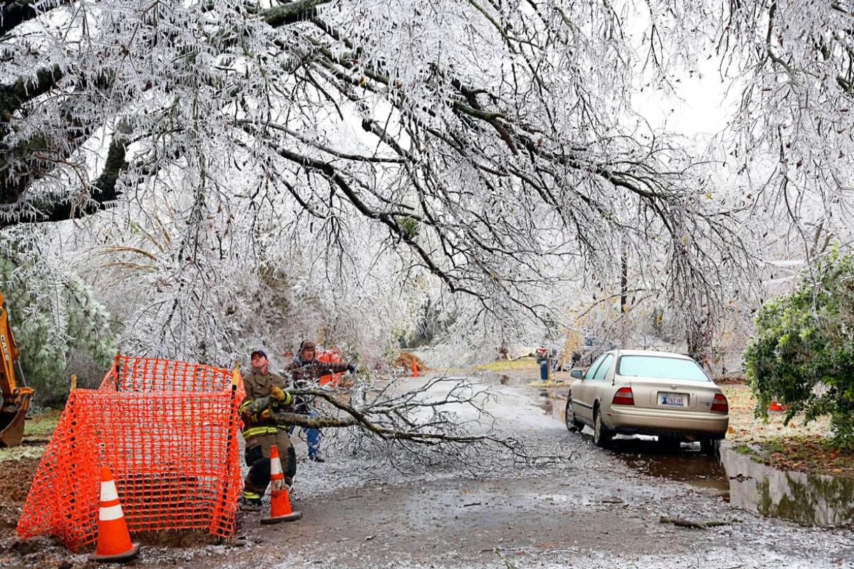 A firefighter and a homeowner work together to clear a street of debris from an ice storm Friday in Paris, Texas.