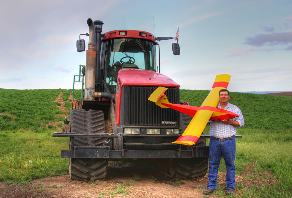 Farmer Robert Blair stands in front of his tractor holding an unmanned aircraft that he built in Kendrick, Idaho.