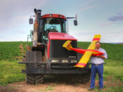 Farmer Robert Blair stands in front of his tractor holding an unmanned aircraft that he built in Kendrick, Idaho.