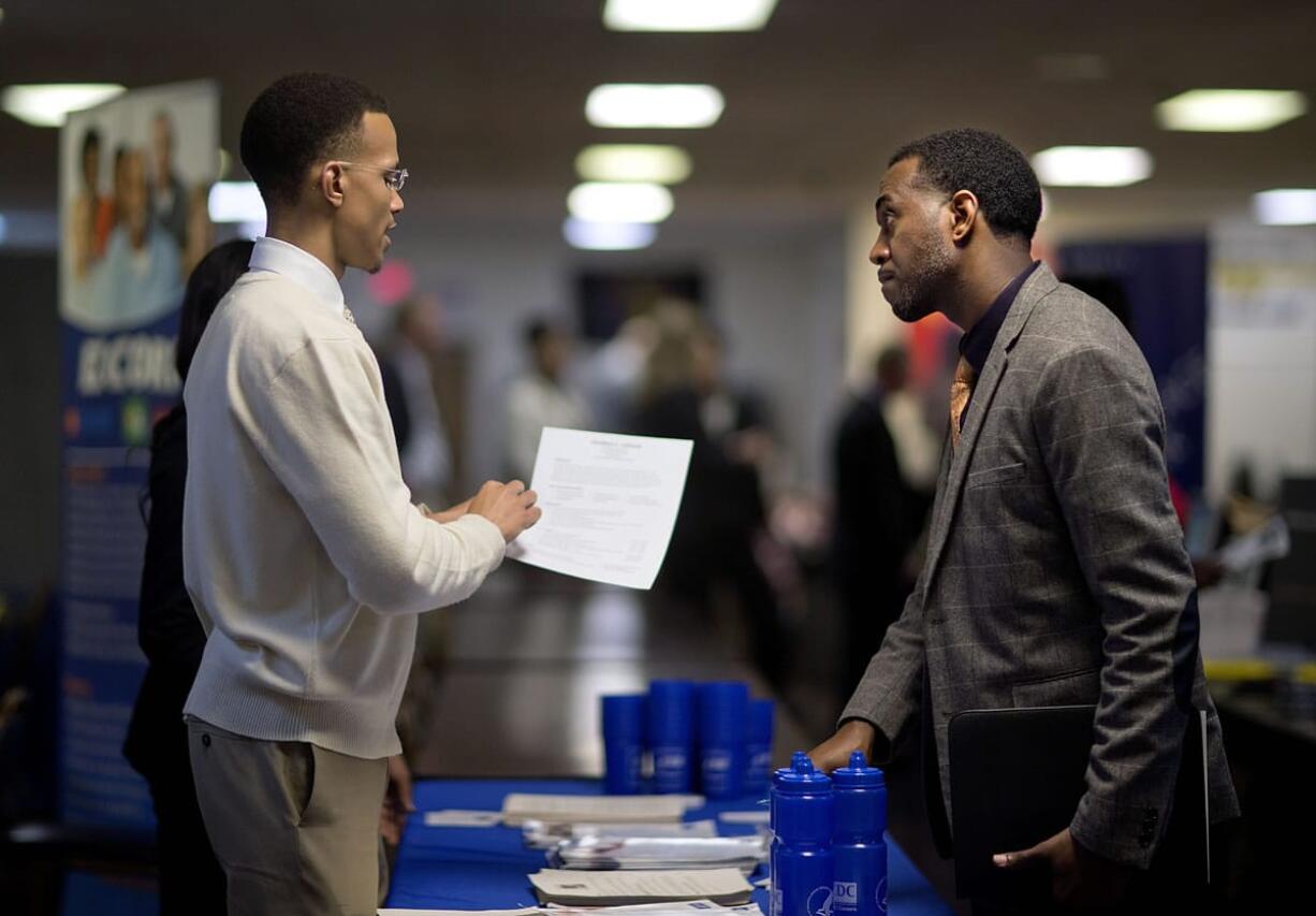 Retired U.S. Air Force Master Sgt. Thomas Gipson, of Atlanta, right, has his resume looked over Nov. 14 by Ralph Brown, a management and program analyst with the Centers for Disease Control and Prevention, during a job fair for veterans at the VFW Post 2681,Marietta, Ga. The U.S. job market is proving sturdier than many had thought.  Solid job growth in November cut the U.S.