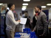 Retired U.S. Air Force Master Sgt. Thomas Gipson, of Atlanta, right, has his resume looked over Nov. 14 by Ralph Brown, a management and program analyst with the Centers for Disease Control and Prevention, during a job fair for veterans at the VFW Post 2681,Marietta, Ga. The U.S. job market is proving sturdier than many had thought.  Solid job growth in November cut the U.S.