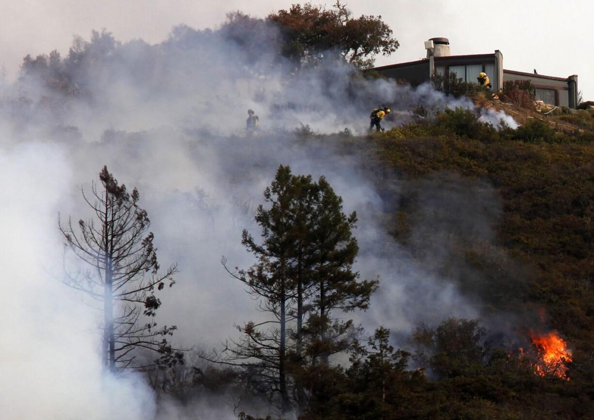 Firefighters defend a home Monday as a wildfire burns in the Pfeiffer Ridge area in Big Sur, Calif.