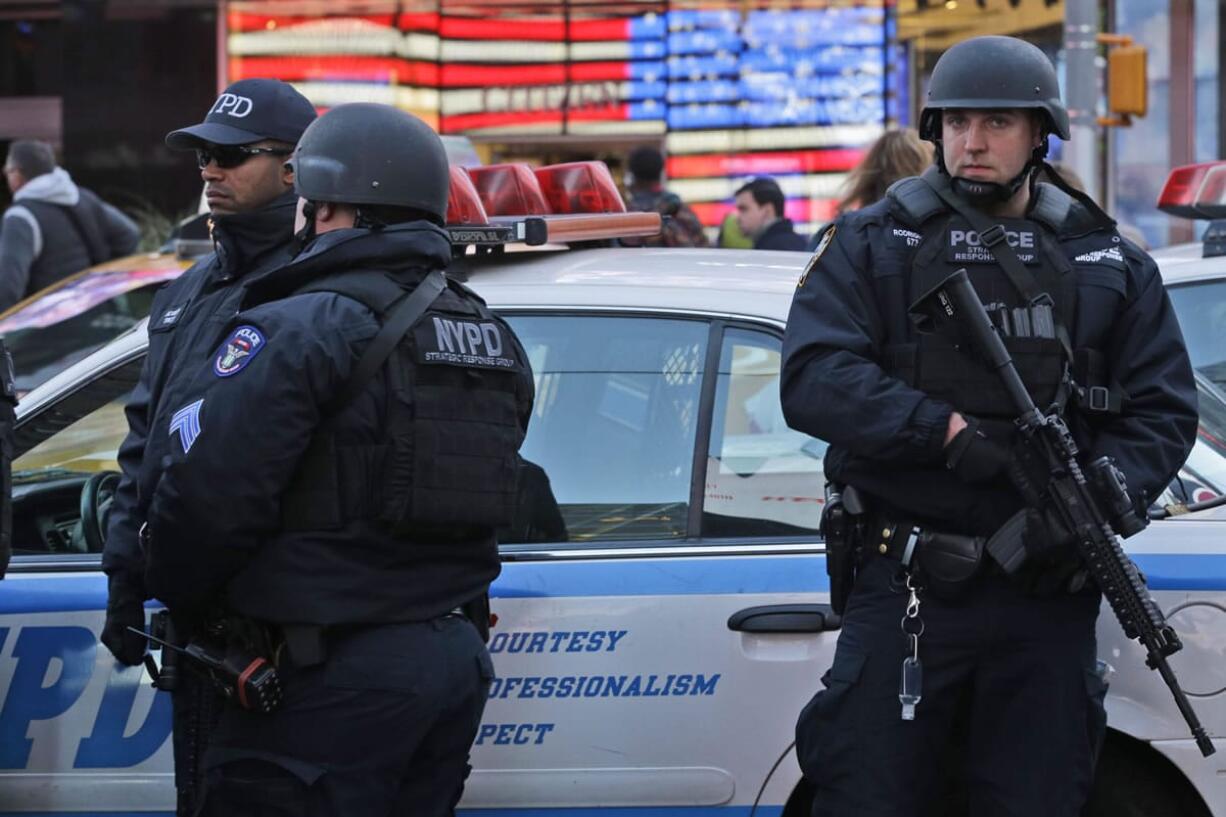 Heavily armed New York city police officers with the Strategic Response Group stand guard in New York's Times Square, Saturday, Nov. 14, 2015. Police in New York say they've deployed extra units to crowded areas of the city "out of an abundance of caution" in the wake of the attacks in Paris, France.