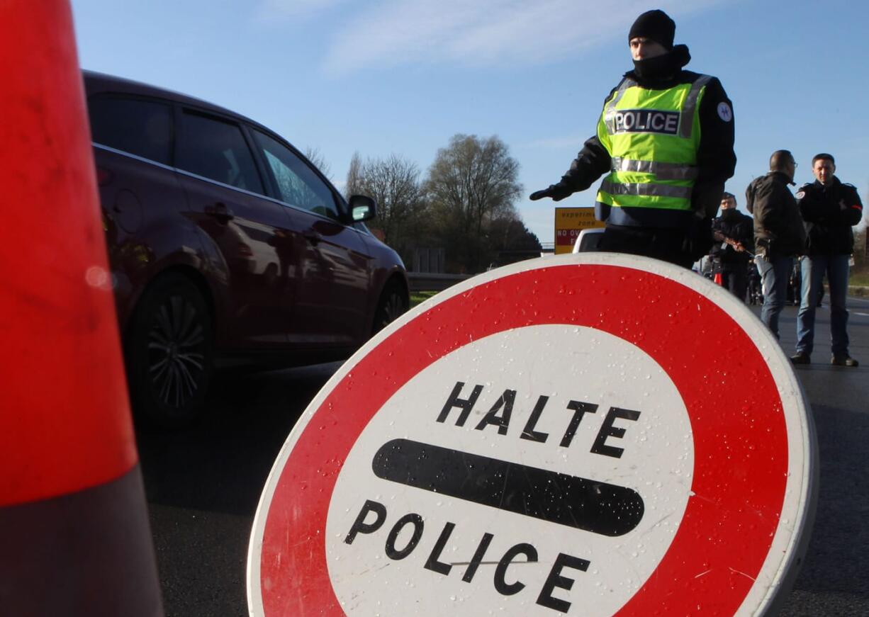 A French police officer slows down the traffic at the border between France and Belgium on Monday in Neuville-en-Ferrain, France.