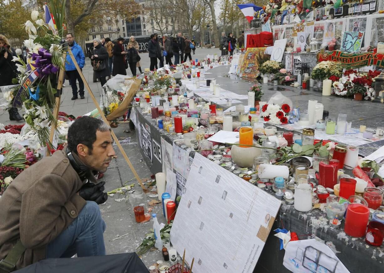 A man reads messages Friday at the Place de la Republique in Paris. A subdued France paid homage Friday to those killed two weeks ago in the attacks that gripped Paris in fear and mourning, honoring each of the 130 dead by name as the president pledged to &quot;destroy the army of fanatics&quot; who claimed so many young lives.